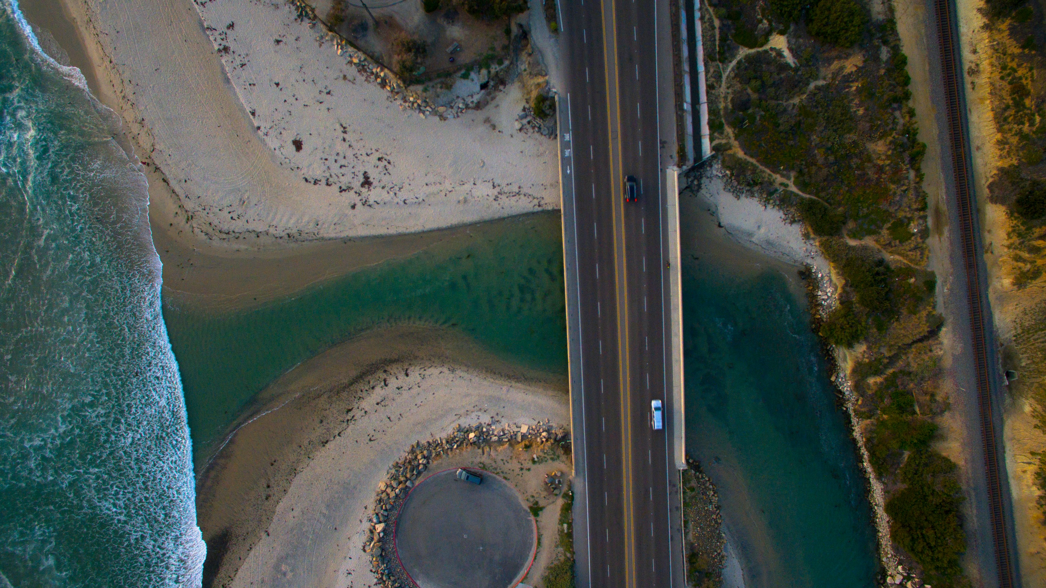 aerial photography of black and white vehicles on road between body of water and